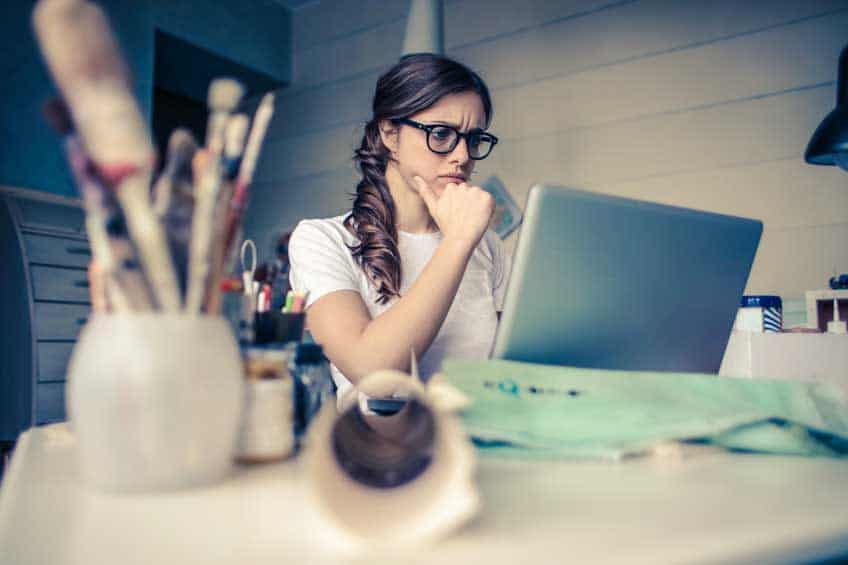 Girl with focused look on her face, staring at laptop