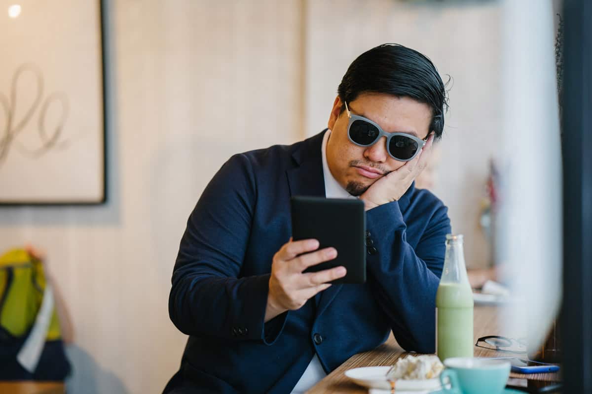 Bored man looking at phone in coffee shop