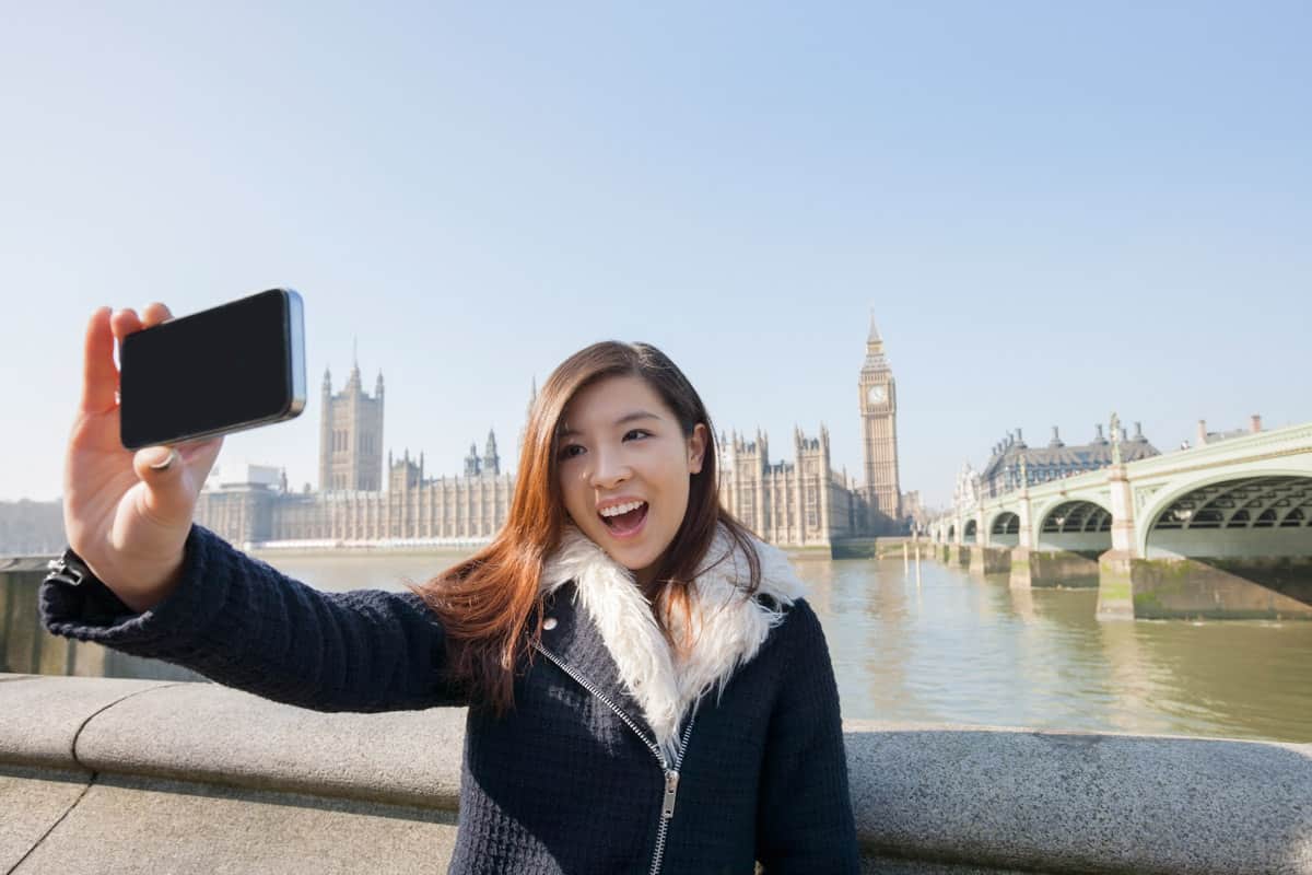 Happy young woman taking self portrait through cell phone