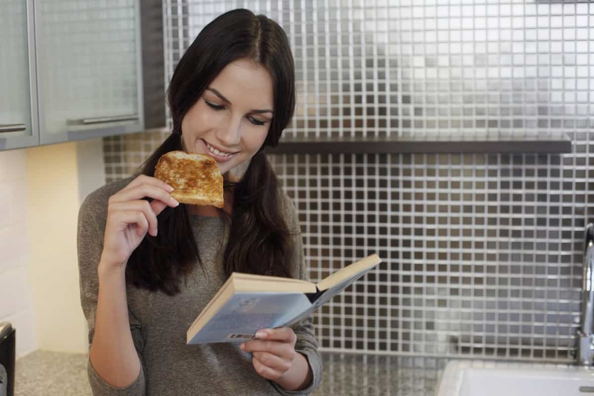 Woman eating toast while reading book
