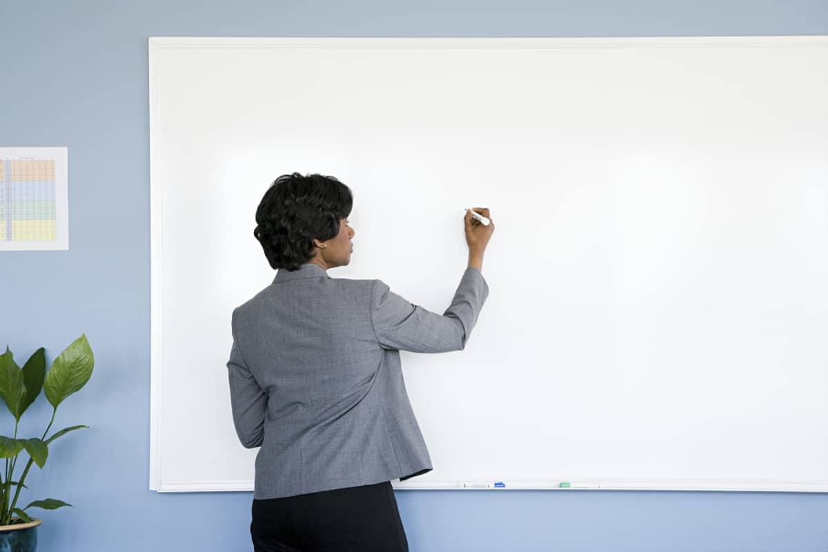 Professor writing on whiteboard with marker